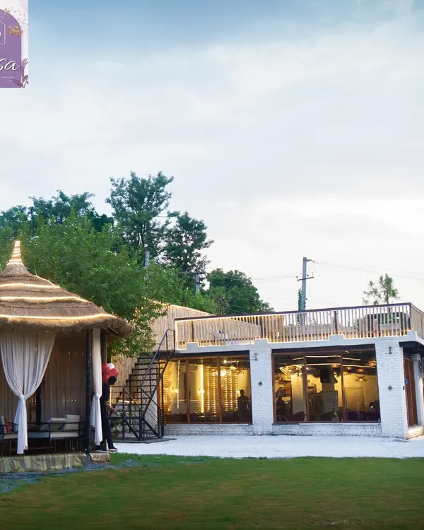 A beautiful daytime view of the property. This shot shows the lush lawn, a private bamboo cabana, and the indoor hall with its rooftop terrace, giving you a sense of the different spaces available.