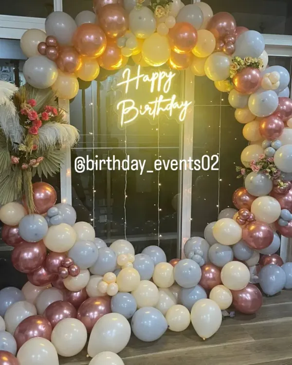A full view of our elegant ring backdrop, featuring a mix of pastel blue, cream, and rose gold metallic balloons. This setup includes dried palm leaf accents and fairy lights for a soft, bohemian touch.