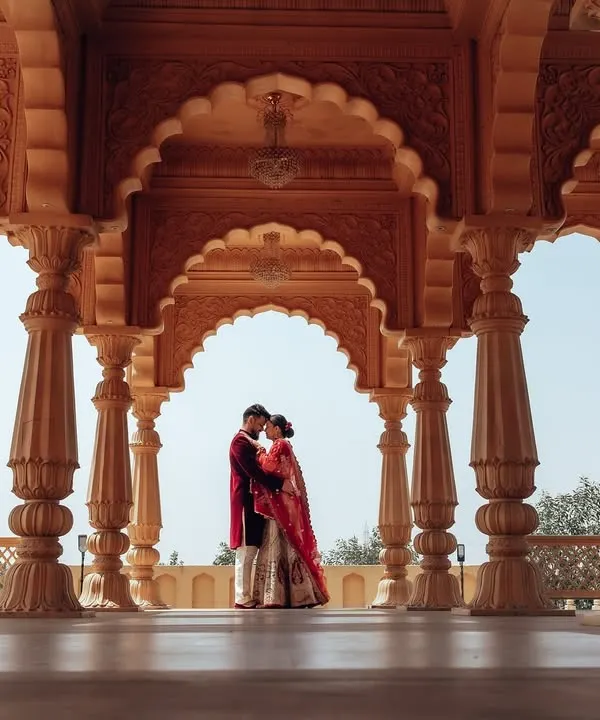 A classic, wide-angle shot capturing the scale of a royal courtyard. The symmetrical arches frame the couple perfectly, creating a powerful and majestic pre-wedding photograph.