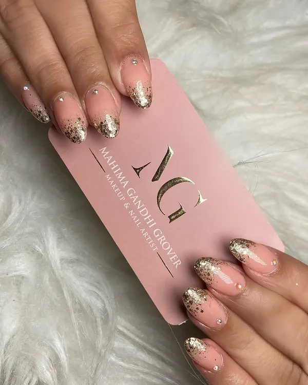 A close up of sparkling elegance. These almond shaped nails feature a beautiful glitter ombre effect with delicate stonework, a popular and glamorous choice for festive occasions.
