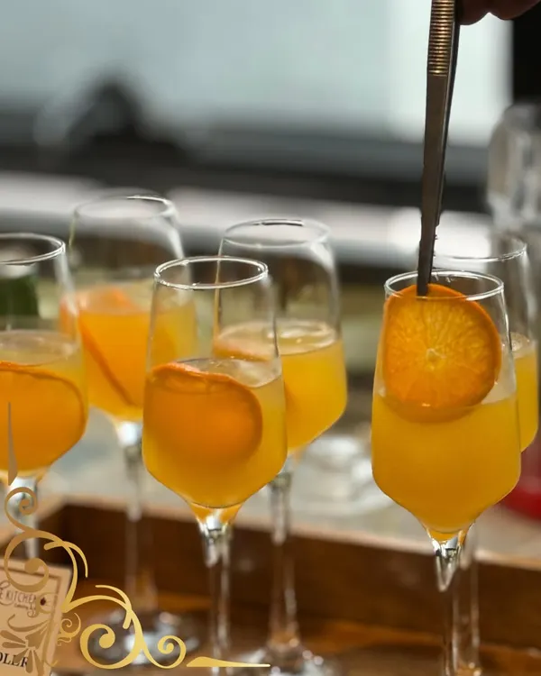 A refreshing orange spritz, garnished with a fresh orange slice. A simple, elegant, and delicious welcome drink for any event.