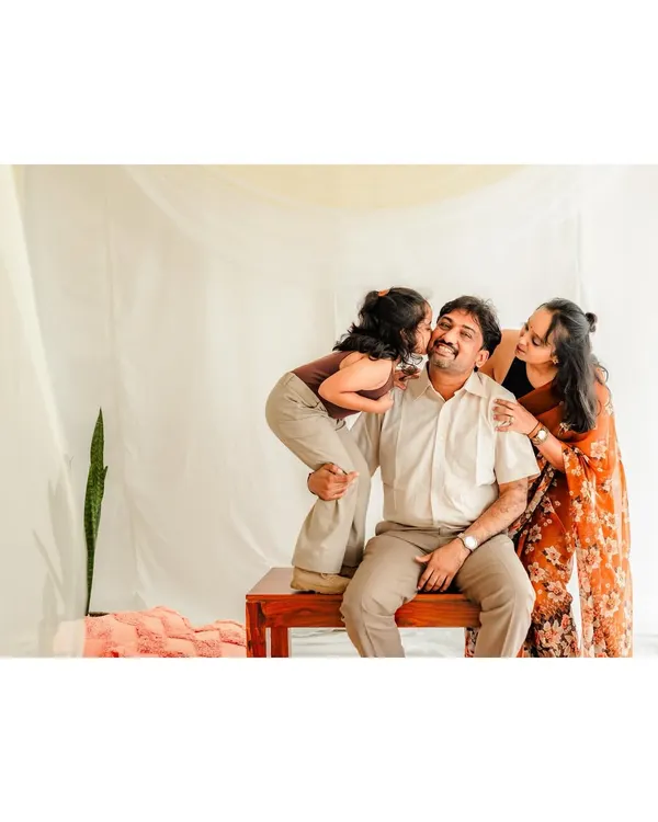 A heartwarming studio shot of a family, with the daughter planting a sweet kiss on her father's cheek. Our goal is to create a comfortable atmosphere where these loving, spontaneous moments can happen.