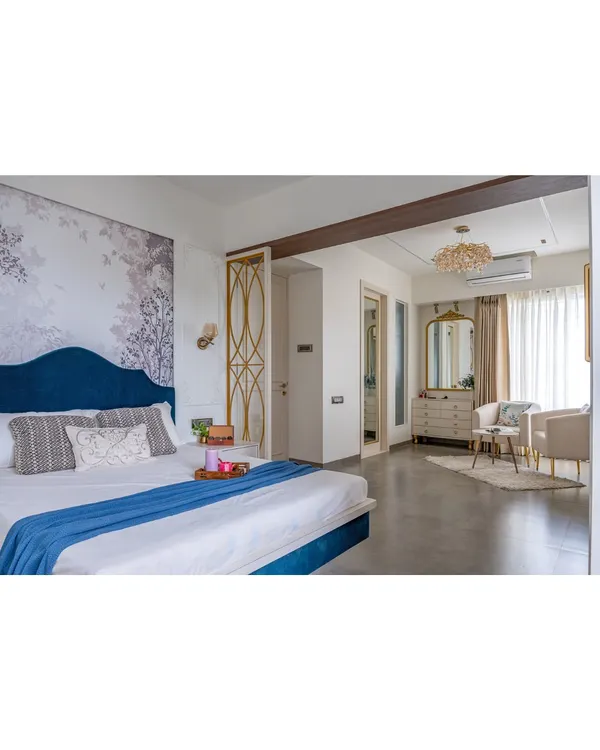 A wide view of a luxurious master bedroom, showing the sleeping area and a separate, cozy seating nook by the window. The design creates distinct zones for rest and relaxation within a single room.