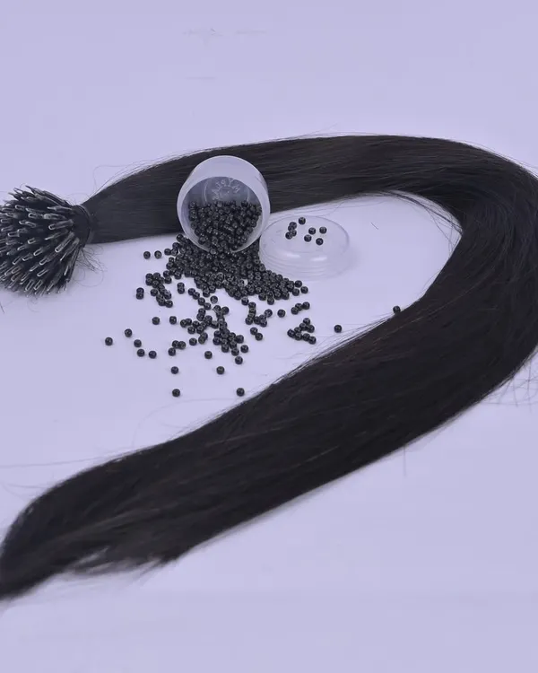 This image shows a bundle of I-tip hair extensions along with the nano beads used to attach them. These tiny beads ensure a discreet and comfortable application for long-lasting volume.