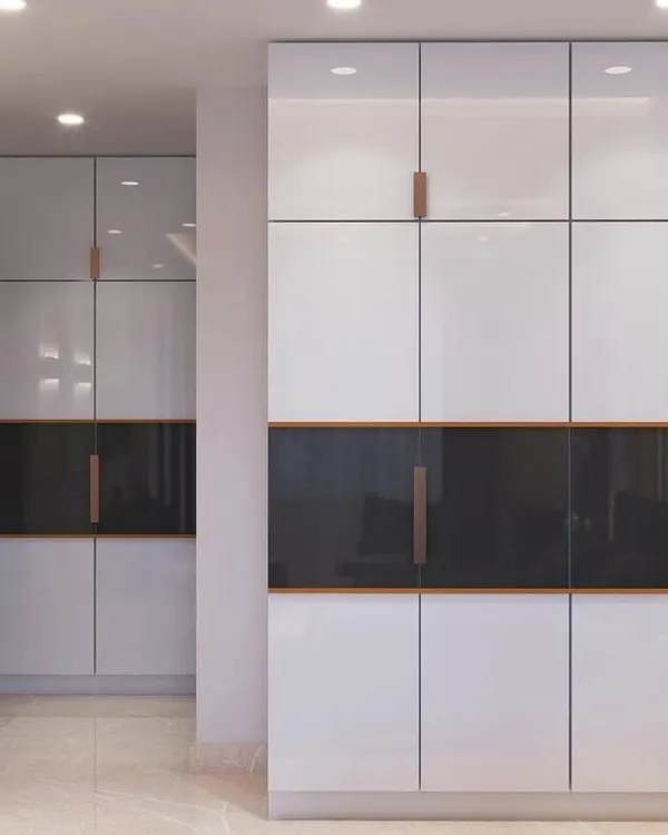 Sleek, high-gloss white wardrobes with minimalist handles and a contrasting dark accent panel, offering a modern and clean storage solution.