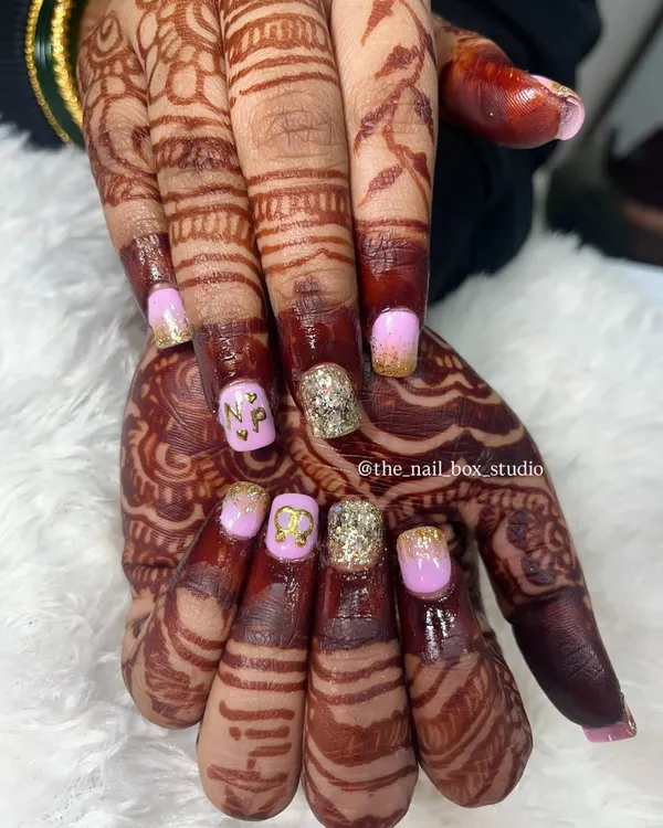 A close up of this personalized engagement nail art. I carefully hand-painted the couple's initials 'N' and 'P' in gold on a soft pink base, paired with a sparkling gold glitter accent nail to match the bride's jewelry.