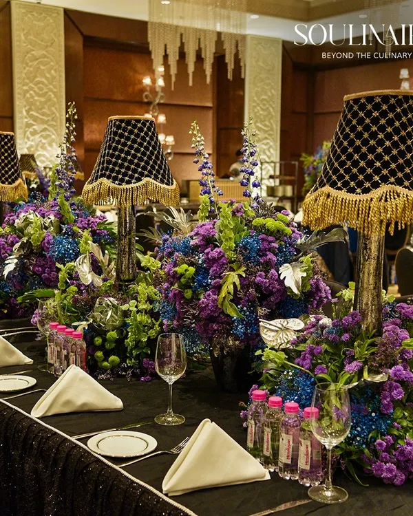 An exceptionally lavish tablescape featuring dramatic floral centerpieces with integrated lampshades. We curate perfect tablescapes that transform any social gathering into a timeless celebration of beauty and grace.