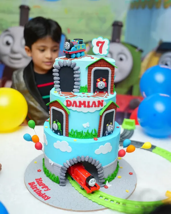 All aboard for Damian's 7th birthday! This three-tier Thomas & Friends cake was a true showstopper, featuring a rotating train centerpiece and edible models of all the favorite characters. The birthday boy's reaction says it all!