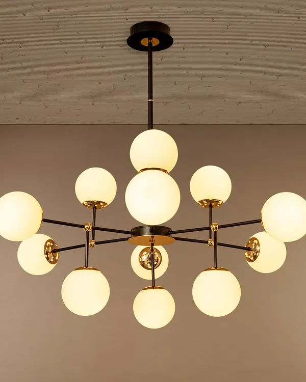 This multi-globe chandelier is designed to make a statement in a living room or over a dining table. The arrangement of opal glass globes on a black and gold frame provides ample, even lighting while adding a distinctly modern, architectural feel to the space.