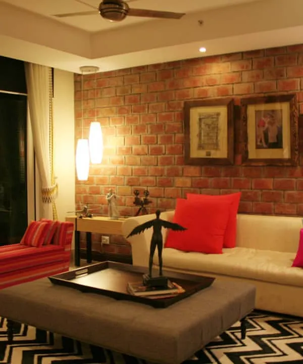 This living room is the perfect example of my design approach. I combined a bold, textured brick wall with a mix of contemporary and vintage furniture, like the striped chaise lounge and classic sofa. The vibrant cushions and graphic chevron rug bring an energetic yet cosy feel to the entire space, creating a home that is full of personality.