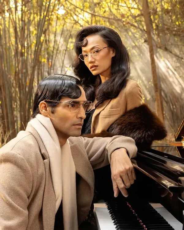 A campaign shot for John Jacobs Eyewear's "Winter Edit," featuring two models in a romantic, vintage-inspired setting we created with a piano and atmospheric fog.