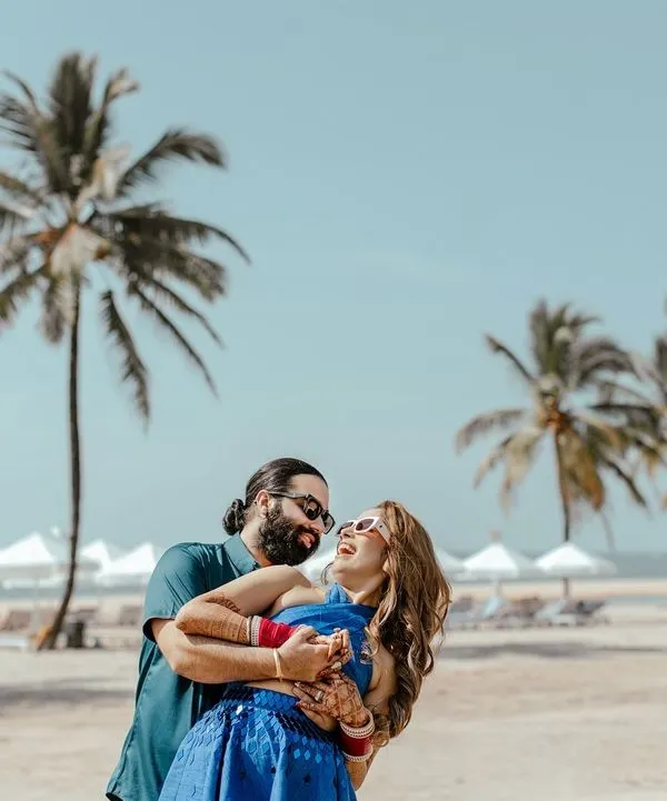 A moment of pure laughter and joy between the couple on a sunny Goa beach, the perfect candid shot from a pre-wedding celebration.