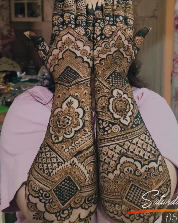 A gorgeous, full-coverage design for the bride's mom. This intricate henna features geometric grids, floral mandalas, and detailed finger work, covering the hands and forearms completely.