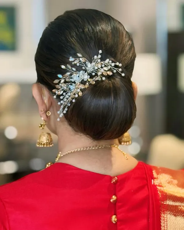 A bun kissed by grace. This sleek and elegant updo is adorned with a beautiful hair accessory, perfect for a wedding or formal event.