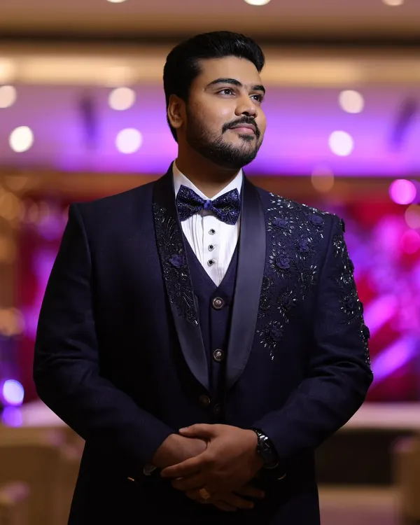 A client looking sharp and confident in his custom navy blue tuxedo. The intricate hand embroidery on the lapel and shoulder adds a layer of bespoke luxury, perfect for a wedding reception.