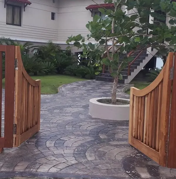 The entrance to your home should be welcoming. I designed this entryway with a custom wooden gate that opens onto a gracefully curved stone path, leading visitors through a lushly planted garden.