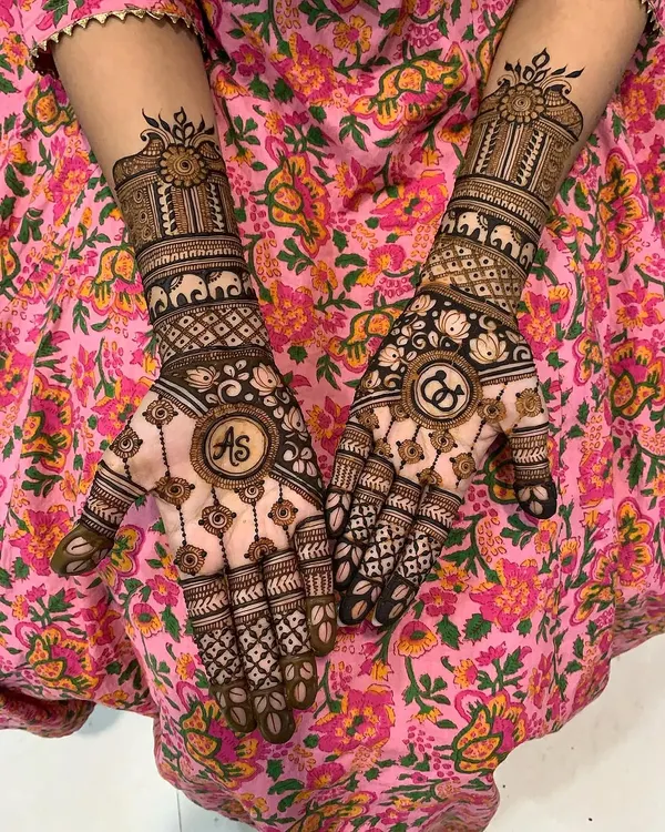This design beautifully incorporates the couple's initials, "AS" and "CD," into circular frames on the palms. The surrounding patterns include elephants and lotuses for a traditional touch.