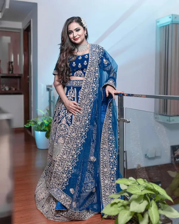 This peacock blue velvet lehenga is pure royalty. The heavy silver and pink embroidery makes it a perfect choice for a bride's reception or a grand wedding event.