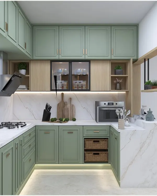 A beautiful U-shaped kitchen in a soft mint green, featuring classic shaker-style cabinets and a white marble-effect countertop. The design includes a breakfast counter and open shelving for a light, airy feel.