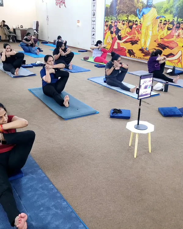 A moment of focused stretching in our group class. This seated twisting pose, Marichyasana, is excellent for improving spinal flexibility and aiding digestion. Notice how some students are also connected to our live online session.
