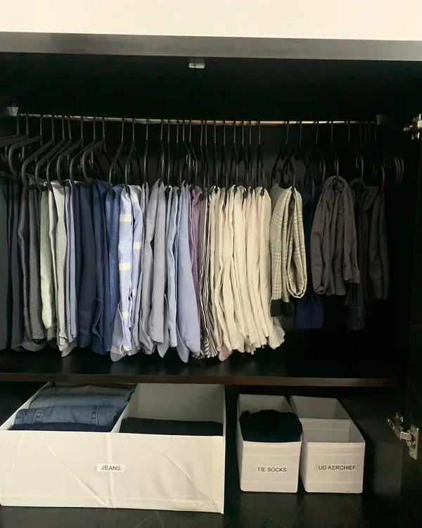 A clean and efficient system for a man's wardrobe. Trousers are hung on uniform hangers, while labeled bins below store jeans, socks, and handkerchiefs. This is organization that performs.