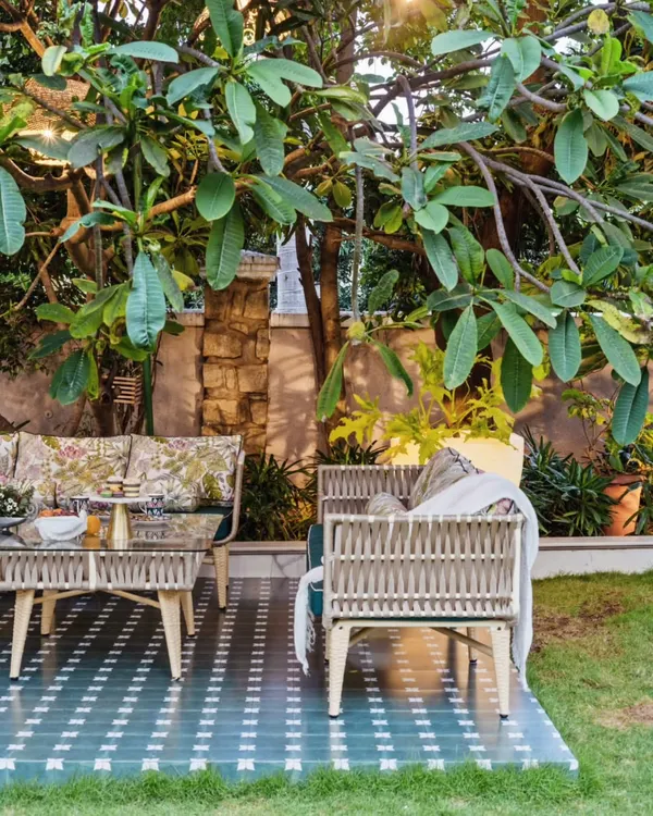 A perfect spot for morning coffee in a lush garden. The custom-made woven furniture and patterned tile deck are nestled under a canopy of green leaves, creating a serene and magical retreat.