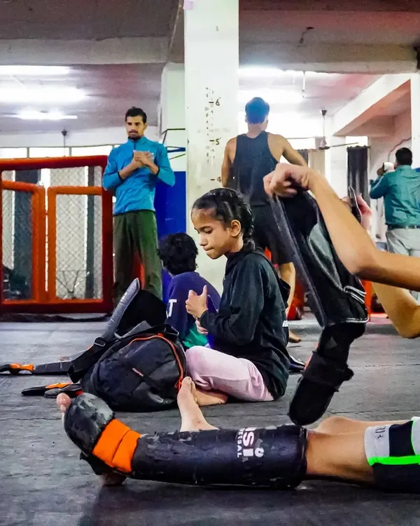 These kids are not weak. They are learning to face challenges head-on. Here, they are getting ready for their kickboxing drills, putting on their shin guards and preparing for practice.