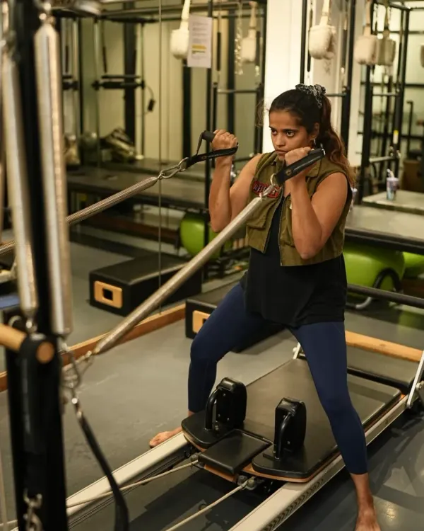Indian cricketer Harmanpreet Kaur works on the reformer and chair, demonstrating exercises that build unilateral strength and stability. This is crucial for athletes to correct muscle imbalances and prevent injuries.