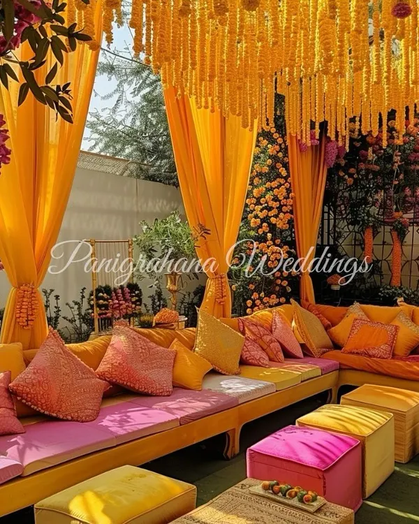 A mesmerizing Mehendi decor setup. We went all out with custom-dyed cushions, a ceiling of marigold strings, and blush pink accents to create this vibrant, layered look.