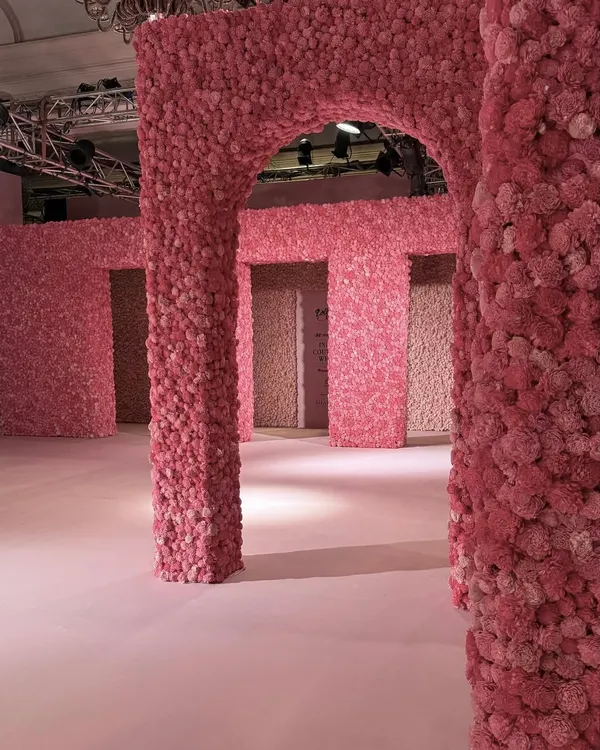 For Dolly J's couture show, I designed an immersive dreamscape of pink floral architecture. This runway set, with its grand arches and columns covered in thousands of blooms, was crafted to transport the audience directly into the romantic heart of the collection.