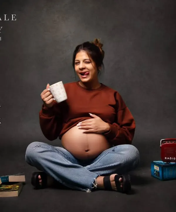 A fun and modern take on maternity photography. This mom-to-be shows off her playful personality and bare bump in a casual outfit, surrounded by books and a retro radio for a personalized touch.