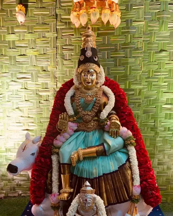 A close-up of a Varamahalakshmi deity we prepared for a home pooja. The goddess is adorned with a beautiful saree and garlands, seated against our signature woven coconut leaf backdrop for a truly divine setup.