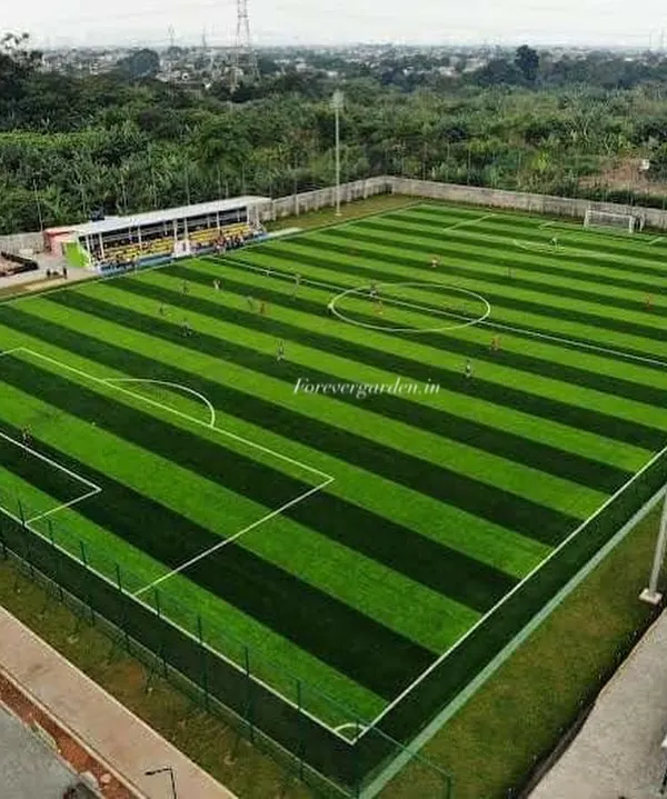 An aerial view of a full-sized football pitch I installed, featuring a two-tone striped pattern. This high-density turf is designed to withstand heavy use while providing excellent ball roll and player safety.