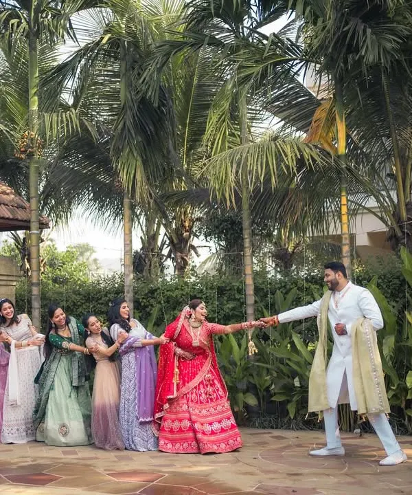 A playful tug-of-war between the groom and the bridesmaids, who are all trying to pull the bride away. A classic, fun-filled wedding moment.