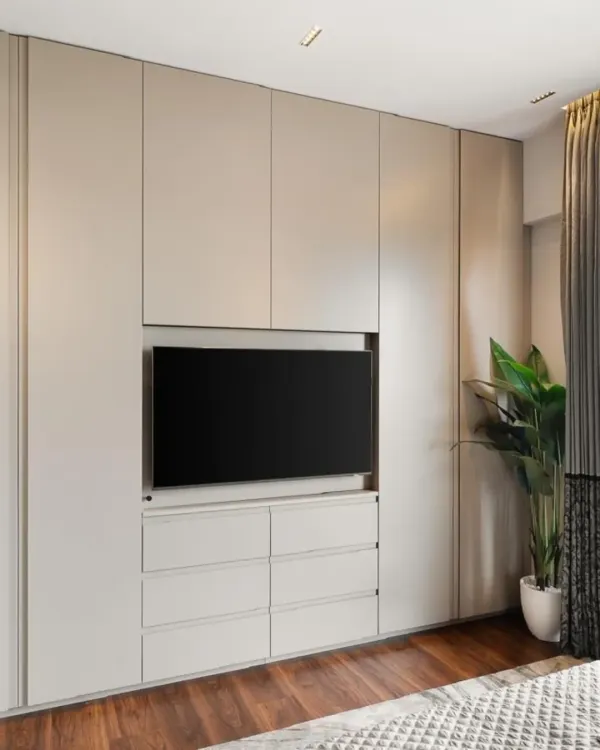 This is a perfect example of an integrated bedroom solution. A full wall is utilized for a custom built-in that includes a wardrobe, drawers for storage, and a dedicated niche for a television, creating a clean and organized media wall.