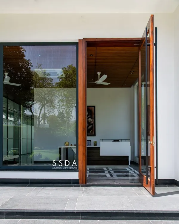 The entrance to The Green Axis, a commercial office I designed. The large pivot door and floor-to-ceiling glass immediately connect the interior reception area to the green landscape outside, setting a tone of openness and tranquility.