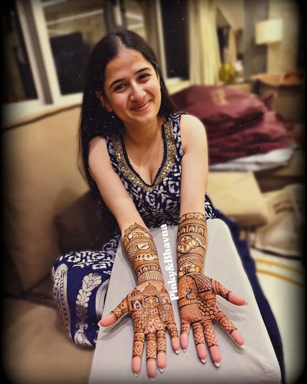 A beautiful bride-to-be showcasing her full bridal mehndi. Both hands are covered in intricate patterns, telling a story that is unique to her.