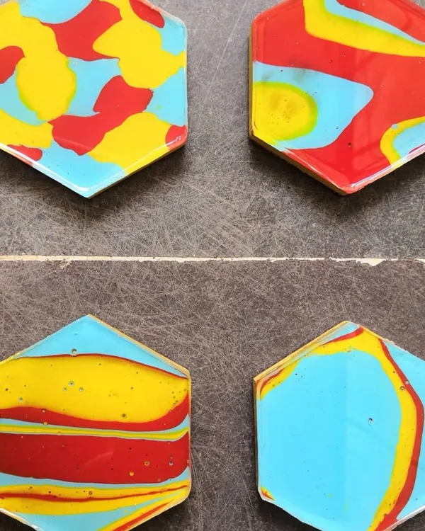 A set of four handmade coasters, each with a completely unique abstract design in primary colors. They are coated with resin for a glossy, durable finish. These are a fun way to add art to your home.