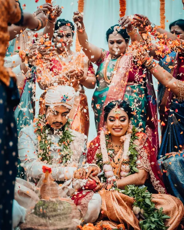 A beautiful, wide-angle shot of a South Indian wedding ritual, capturing the couple surrounded by the joyous blessings of their family and friends.