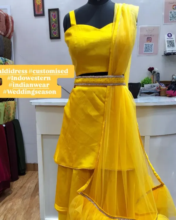 A full view of the custom-designed yellow Haldi dress on a mannequin. This Indo-Western set includes a tiered skirt, crop top, and a delicate net dupatta with a ruffled border, perfect for pre-wedding festivities.