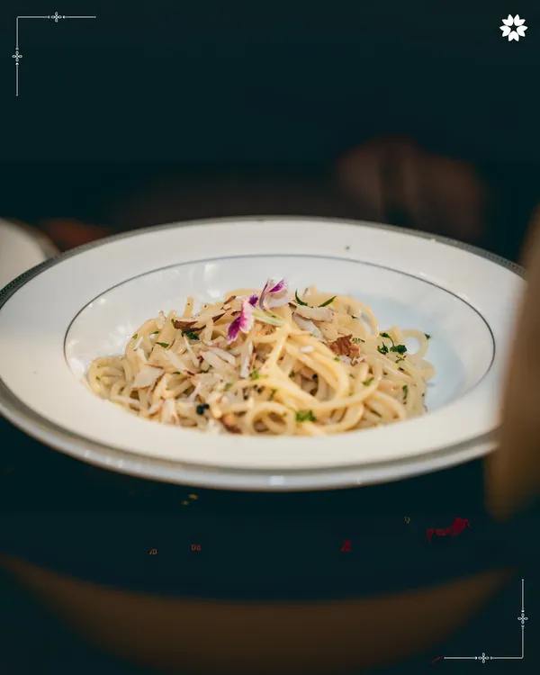 A beautifully plated dish of truffle spaghetti, finished with a delicate edible flower. This is an example of how we elevate a classic dish through thoughtful presentation and premium ingredients for a bespoke engagement menu.
