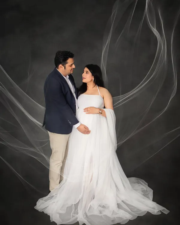 An angelic portrait for a glowing mother-to-be. The flowing white gown and ethereal fabric toss create a sense of grace and beauty, making for a timeless maternity photograph.
