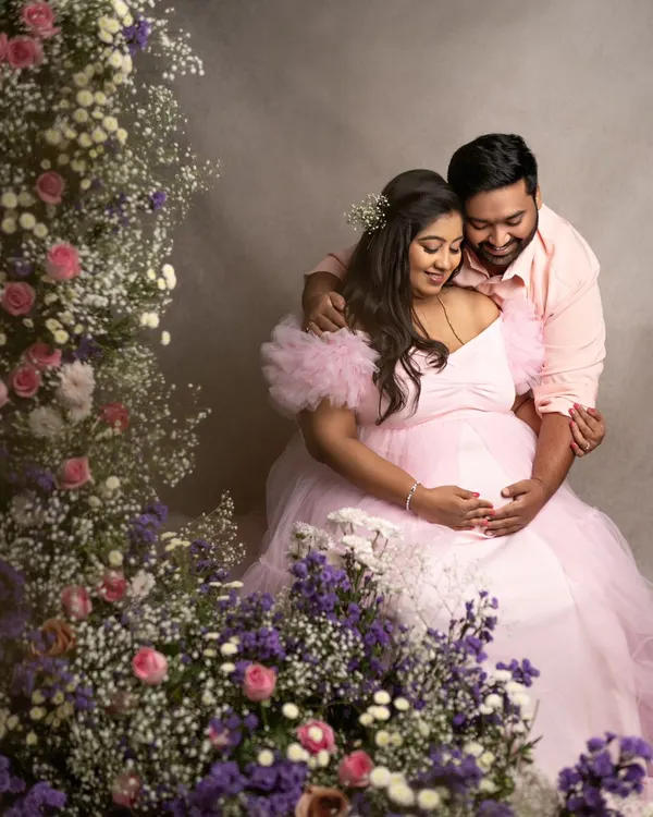 A fairytale moment for this beautiful couple. The mom-to-be in a flowing pink gown, surrounded by a garden of flowers, creates a truly magical and romantic portrait.