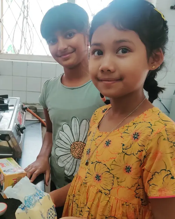 Two girls beam with pride after baking a two-layered vanilla piñata cake for the entire school. They managed the entire process themselves, from planning and shopping to mixing and decorating, experiencing the joy of self-directed work.