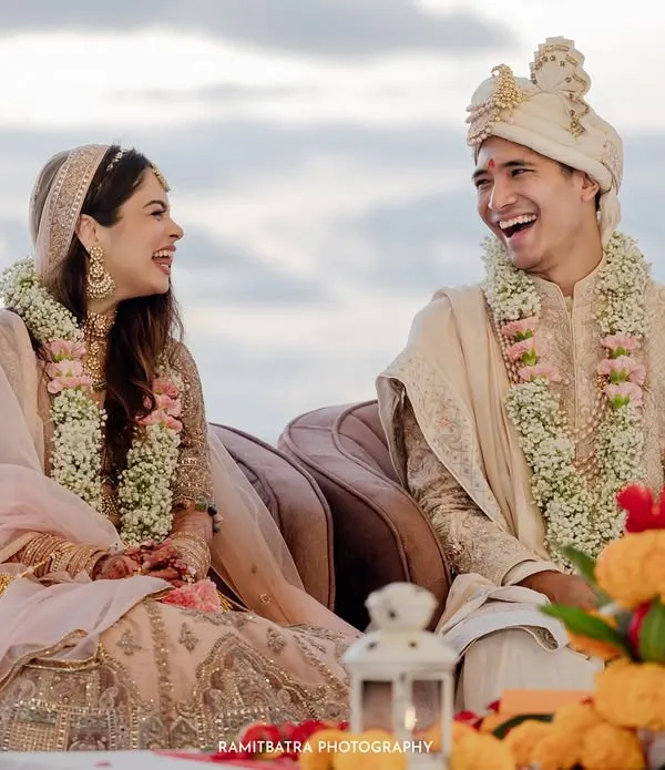 A moment of shared laughter between the bride and groom during their sunset pheras on a beach in Thailand.