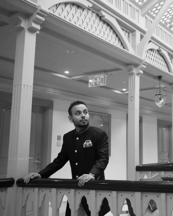 A stylish black and white portrait of the groom in a classic bandhgala. The architectural details and lighting create a sophisticated and timeless look.