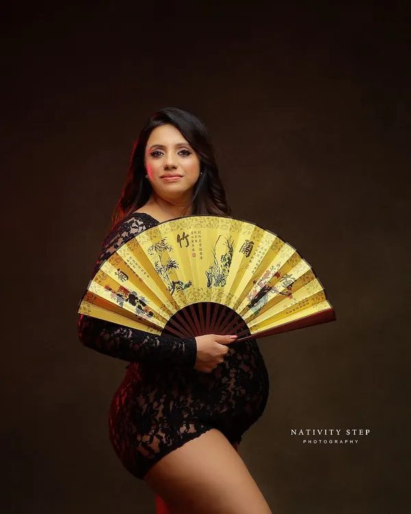 A stunning and unique portrait using a traditional fan as a prop. The red lighting and lace bodysuit create a bold and artistic look.