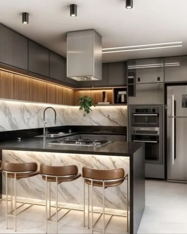 A bold and modern kitchen with dark grey cabinets, a marble-clad breakfast island with under-lighting, and stainless steel appliances for a professional look.