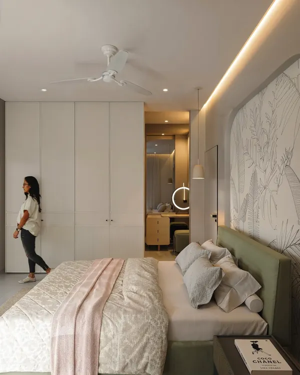 A bright and airy bedroom with a custom arched headboard featuring a line-art mural. The room includes a walk-in wardrobe and a dedicated vanity area.