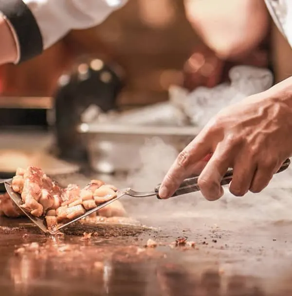 The theater of live cooking is central to our service. Here, one of our chefs expertly prepares Japanese teppanyaki, engaging guests with the sights and sounds of fresh ingredients being transformed on the hot griddle. This interactive culinary performance is a highlight at any wedding or corporate event.